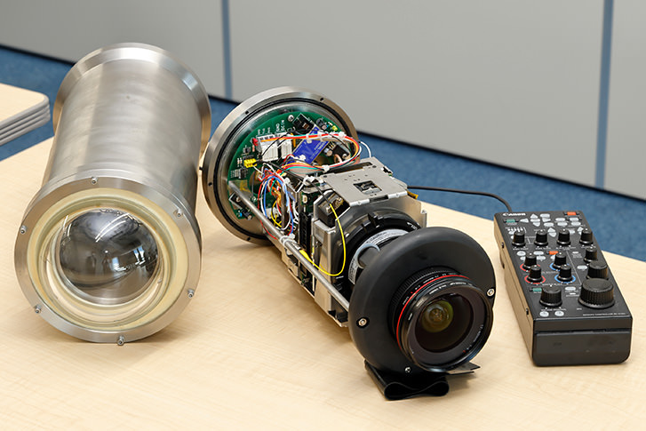 Photos. Canon’s ultra-high-sensitivity multi-purpose camera “ME20F-SH” (center) installed on “Shinkai 6500,” along with the remote controller “RC-V100.” To fit into a housing that withstands pressure at depths of 6,500 m (left), the exterior casing is removed