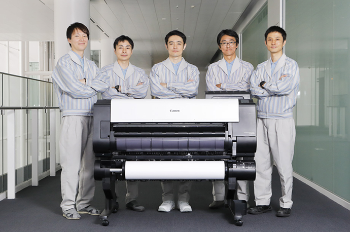 Group photo of developers standing behind the large-format printer.