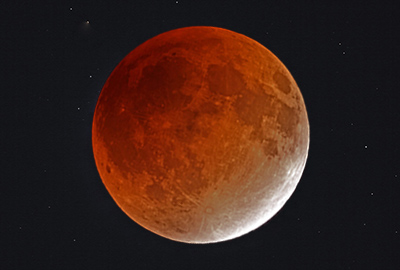皆既月食のとき、地球の影に全面が覆われた月（太陽光の赤い成分が地球の大気で散らばるために赤く見えている）