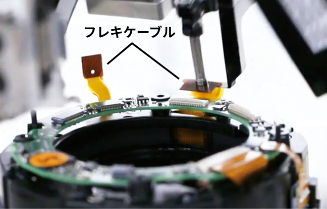 レンズ生産の自動化装置がフレキケーブルを挿入している様子